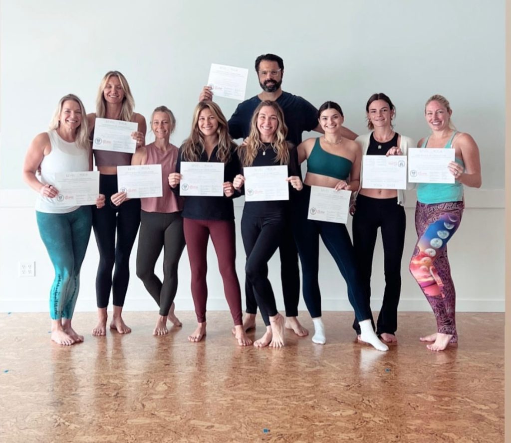 Group holding certificates in yoga studio.