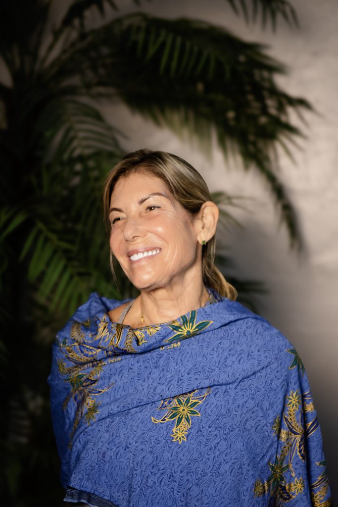Woman in blue shawl with plants.